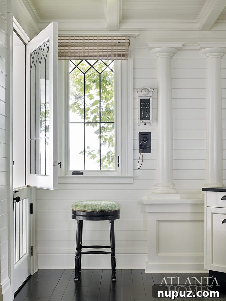 Elegance Meets the Water's Edge: A Jackye Lanham Home 9 A cozy, sun-drenched nook or smaller living area with comfortable seating, a classic chest, and elegant wall art, perfect for quiet reflection.