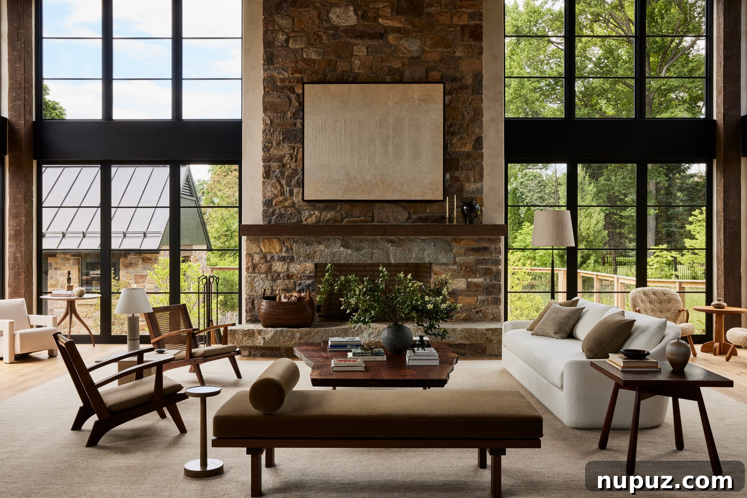 A serene living room designed by Ursino Interiors, featuring a long, tailored sofa in a light neutral tone, complemented by a round wooden coffee table and elegant modern lighting fixtures. The space seamlessly blends contemporary comfort with traditional architectural details.