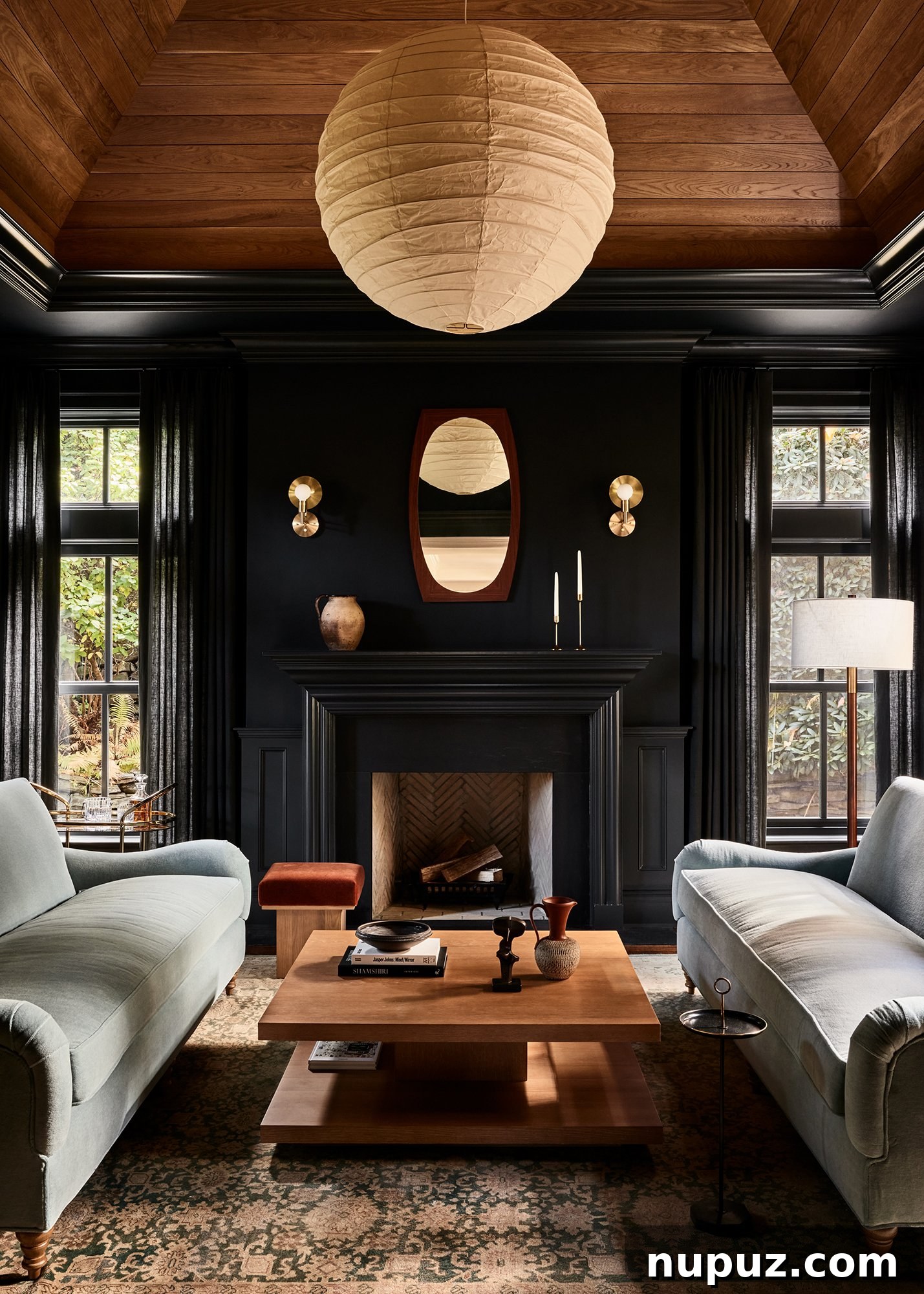A bright and airy Ursino Interiors living room featuring a grand fireplace with a contemporary mirror above, flanked by tailored seating. The use of natural light and light wood accents creates an inviting, open atmosphere.
