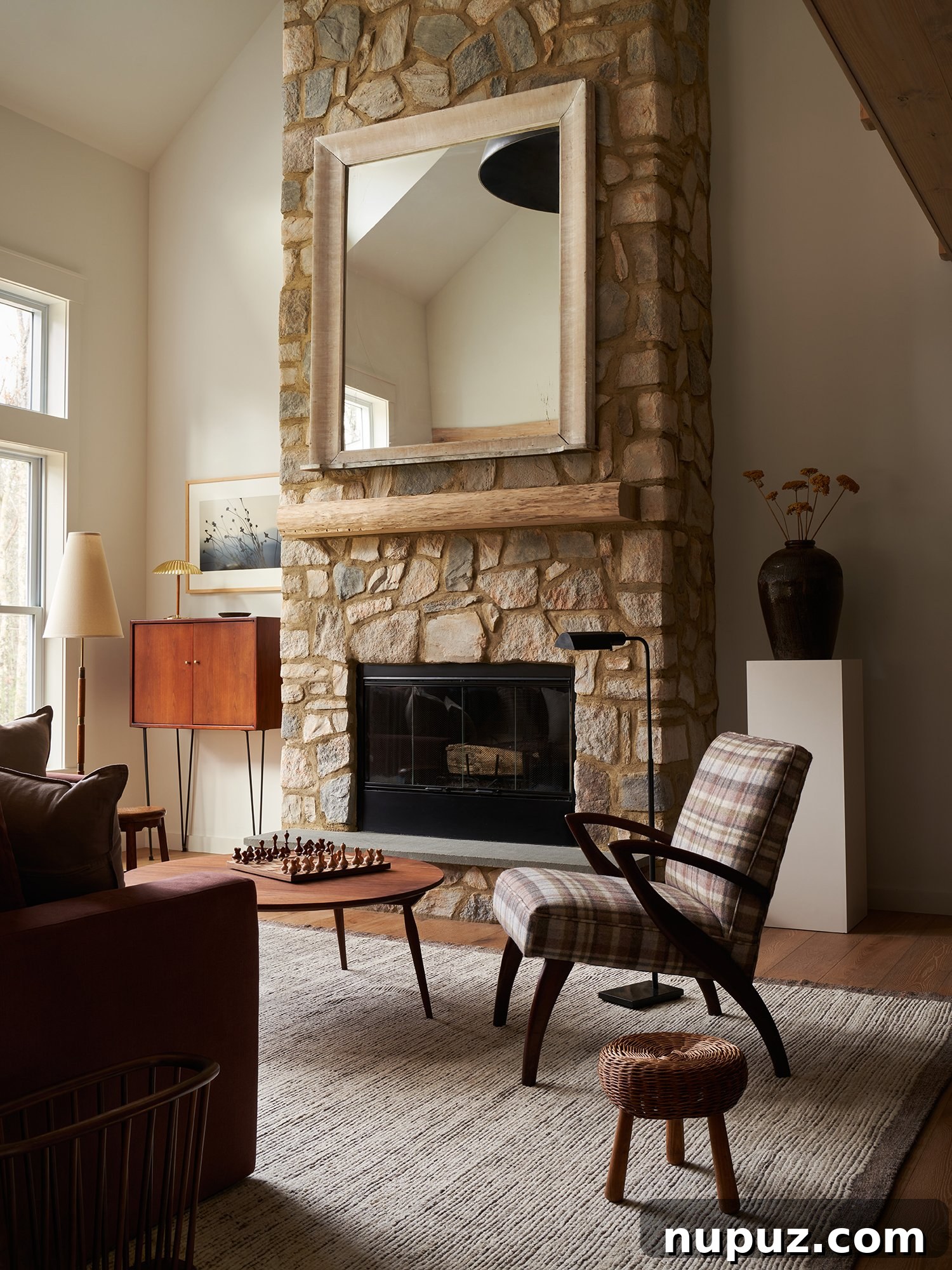 A cozy and chic living room by Ursino Interiors, featuring a dark, inviting sofa, a unique round coffee table, and layered textiles. The room's charm is enhanced by natural light and carefully chosen decorative elements.