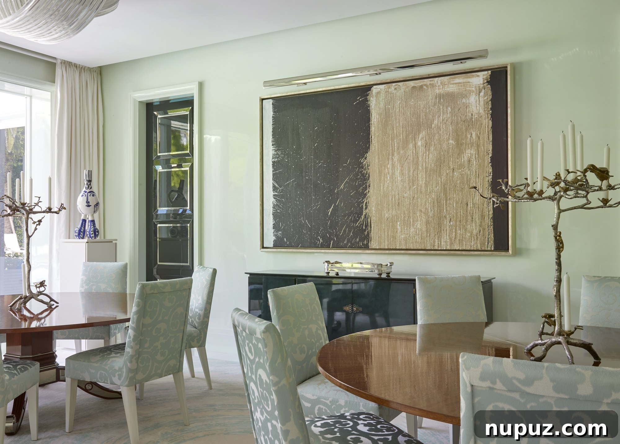 Inside a Palm Beach Home Redefining Modern Elegance 9 Luxurious round dining table in a beautifully appointed dining room, featuring modern art and an elegant chandelier, perfect for entertaining.
