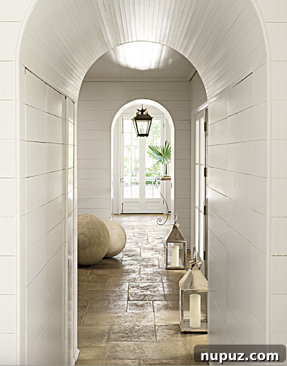 Stunning arched doorway in an elegant entry hall, showcasing intricate architectural details and large wooden decorative spheres by Paul Bates Architecture and Liz Hand Woods Interior Design.