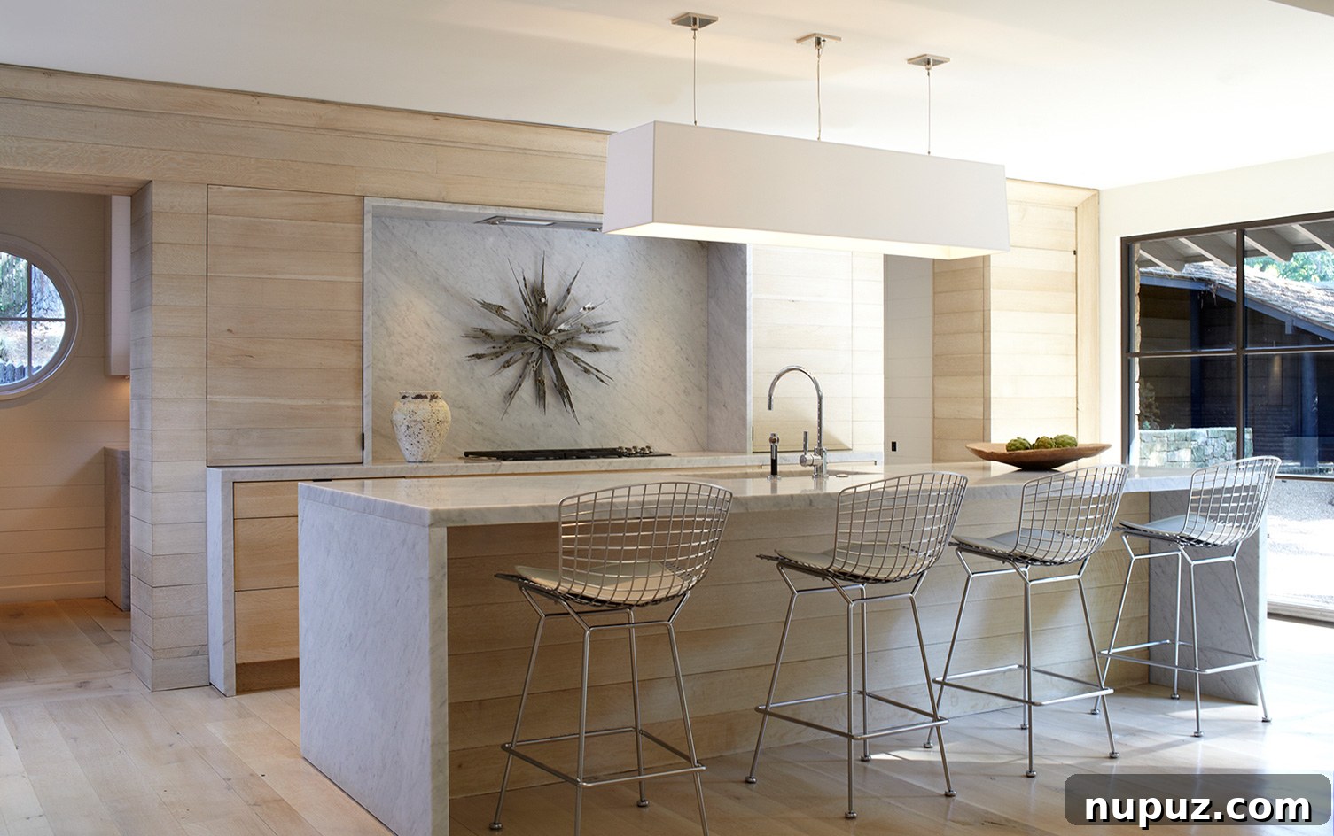 Exquisite kitchen design by Paul Bates Architect and Betsy Brown Interiors, showcasing blonde wood cabinetry complemented by elegant honed marble countertops.