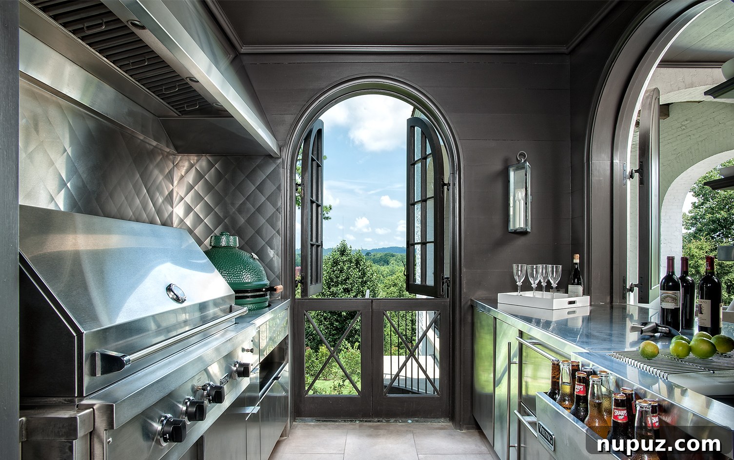 Modern outdoor kitchen with sleek stainless steel appliances and countertops, a sophisticated extension of living space by Paul Bates Architect and Patti Woods Interiors.
