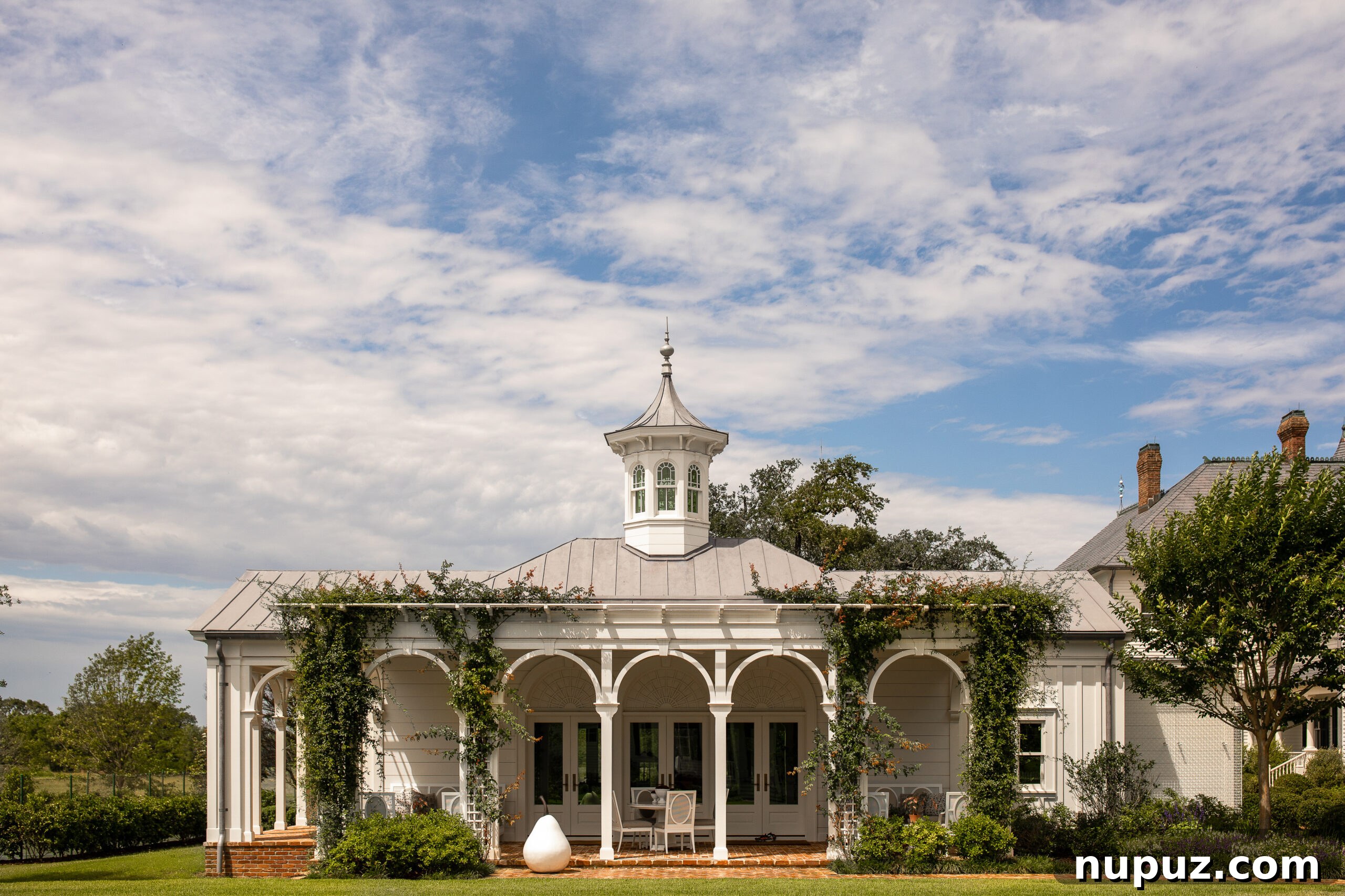 Elegance Redefined: Fusing Modern and Traditional Interior Styles 2 A stunning garden structure with classical arches, a covered porch, and an elegant cupola, showcasing Curtis and Windham's mastery in traditional architectural design.