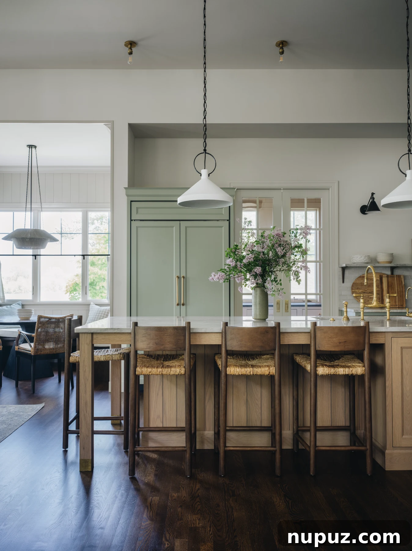 Modern kitchen with blonde wood upper cabinets contrasting with white lower cabinets and dark flooring.
