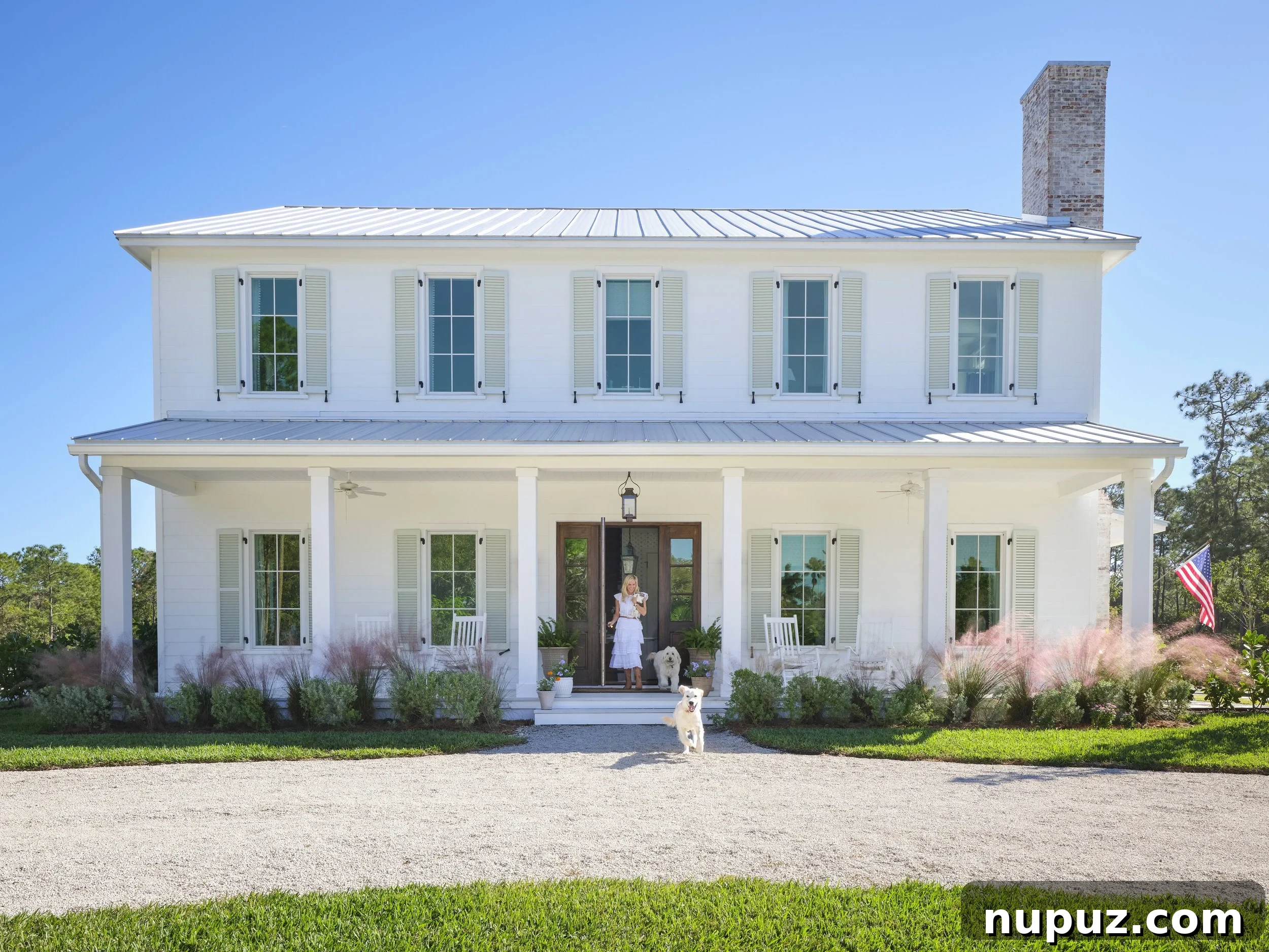 Kara Miller's Farmhouse Retreat 17 Picturesque white farmhouse exterior with a classic tin roof, showcasing the charming architecture and inviting aesthetic designed by Kara Miller. Photography by Brantley Photography.