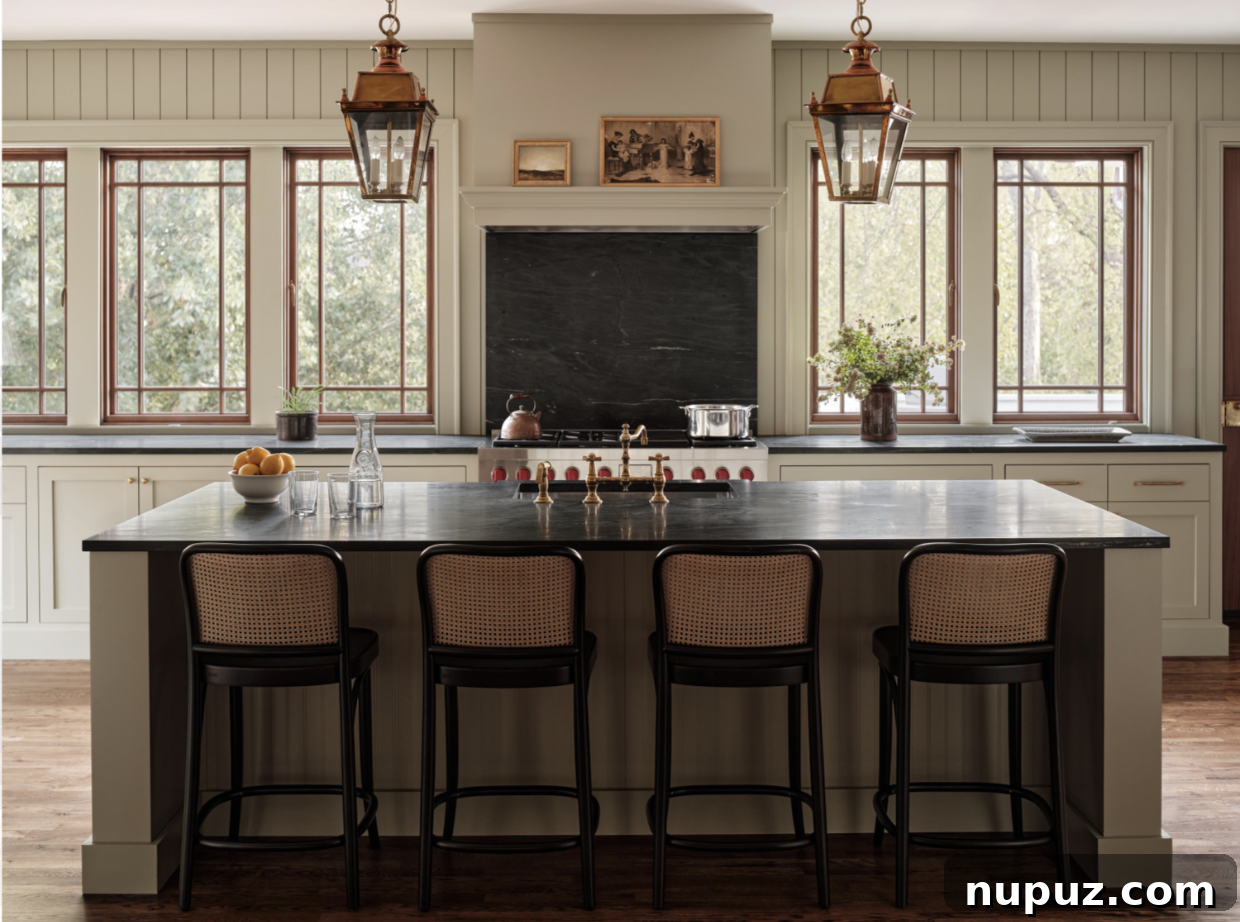 Bright and functional kitchen design by Stephanie Sabbe, with striking lanterns illuminating a central island, custom cabinetry, and a clean, inviting aesthetic ideal for culinary creativity.