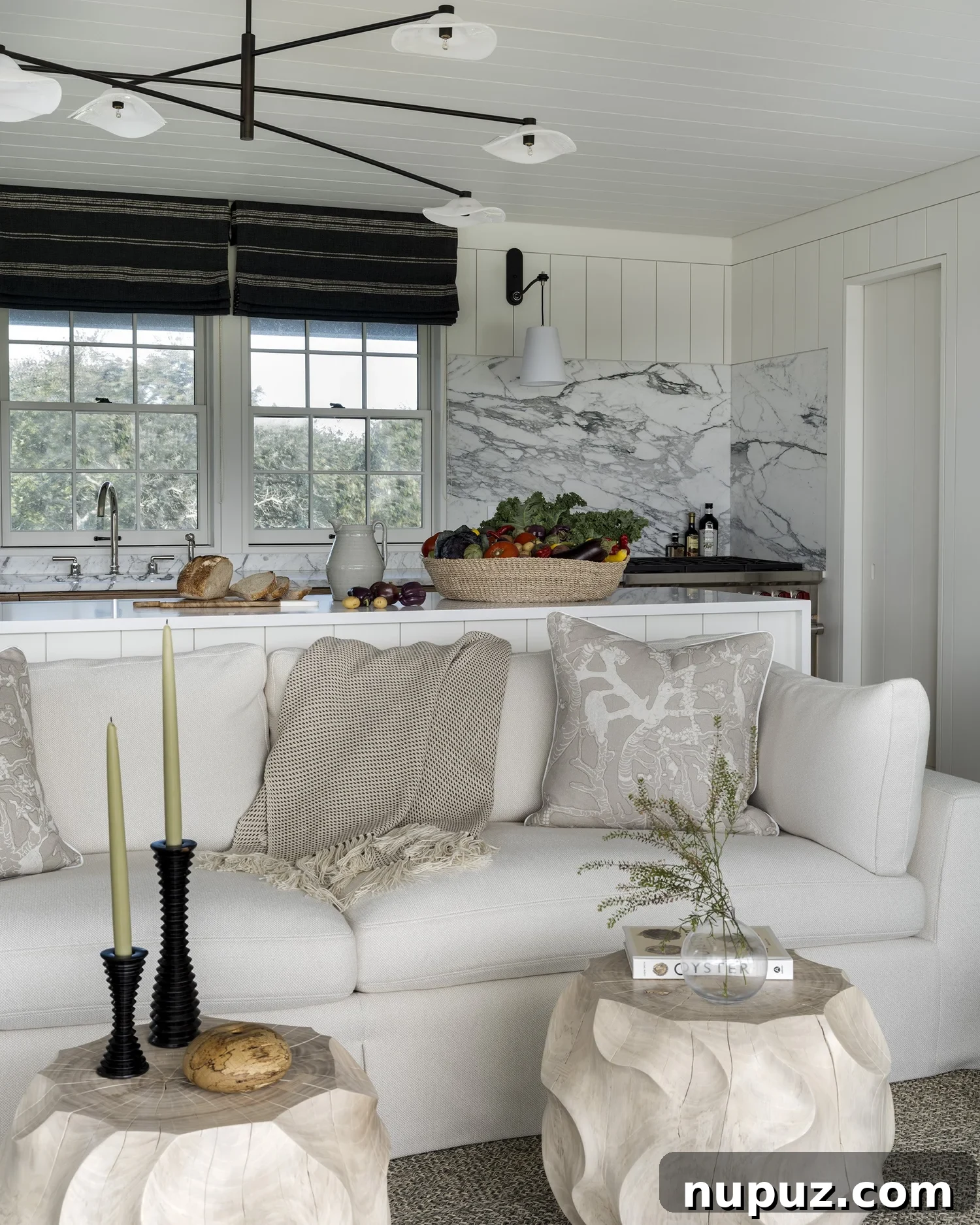 Nantucket's Timeless Coastal Sanctuary Unveiled 3 Bright white kitchen with marble countertops and backsplash, showcasing an open concept layout in a Nantucket coastal home