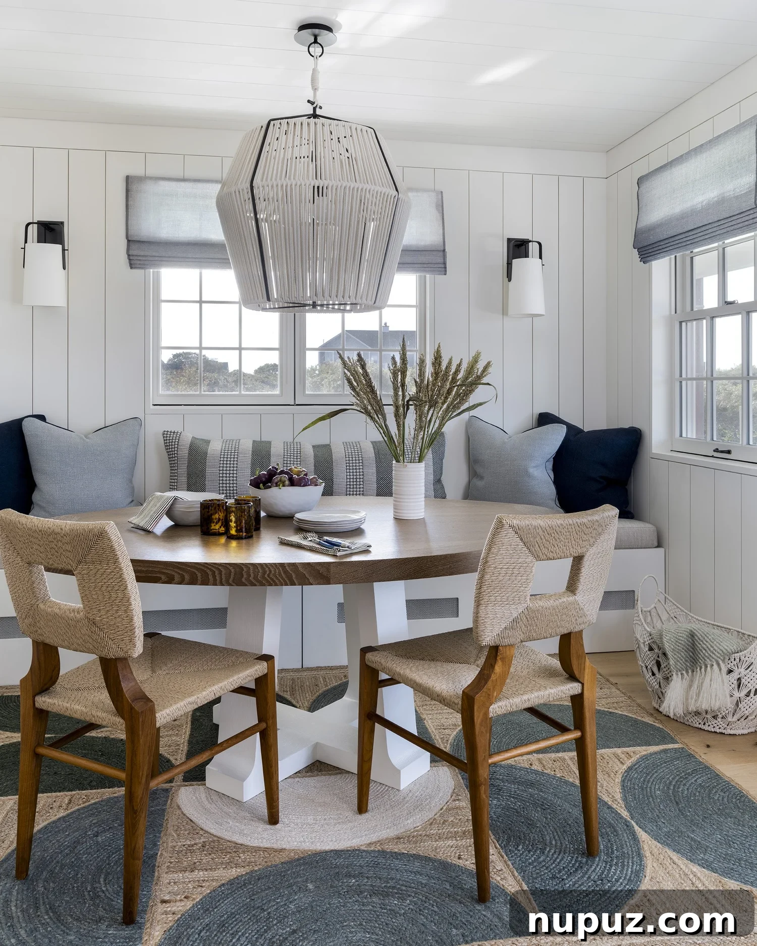 Nantucket's Timeless Coastal Sanctuary Unveiled 5 Charming dining room with a round table, built-in banquette, and classic white paneled walls in a coastal Nantucket residence