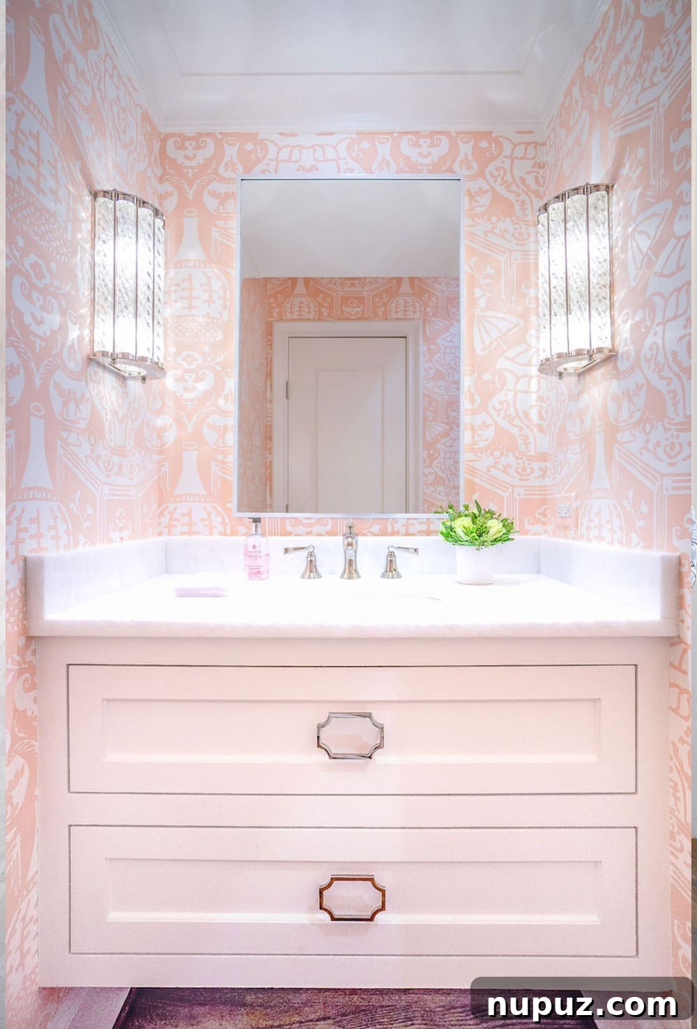 Lindley Arthur's Signature Style: 10 Breathtaking Interiors 8 Lindley Arthur Interiors bathroom featuring a playful pink and white patterned wallpaper, a sleek vanity, and modern lighting.