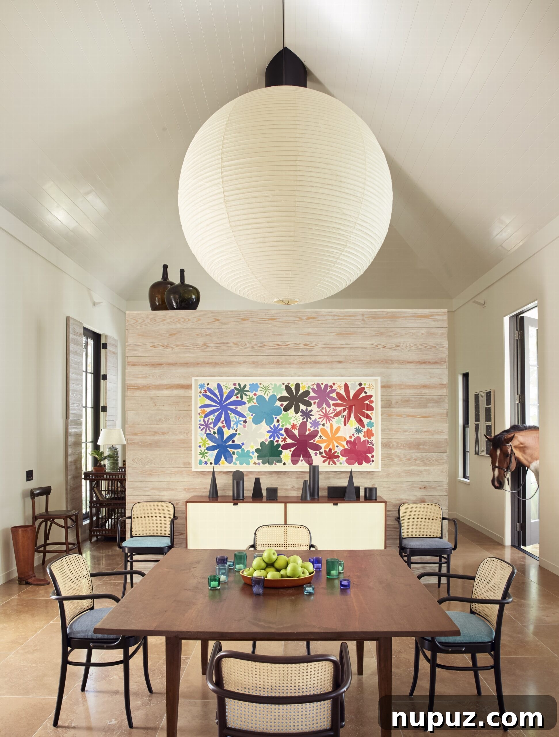 Effortless Elegance: Tom Scheerer's Interior Design Insights 5 A stunning dining room from Tom Scheerer's STILL DECORATING, featuring antique wicker chairs paired with a large, iconic Noguchi oriental lighting fixture, highlighting a blend of textures and global aesthetics.