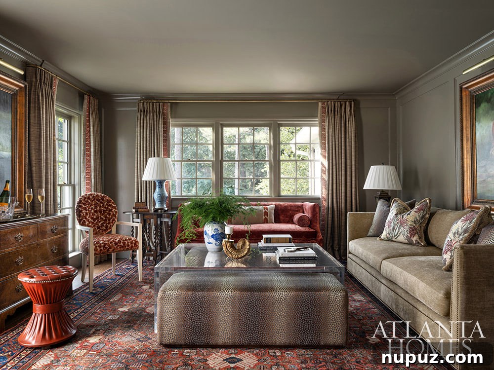 Elegant living room featuring a large, ornate fireplace, classic artwork, and comfortable seating in muted tones, creating a cozy yet luxurious atmosphere.
