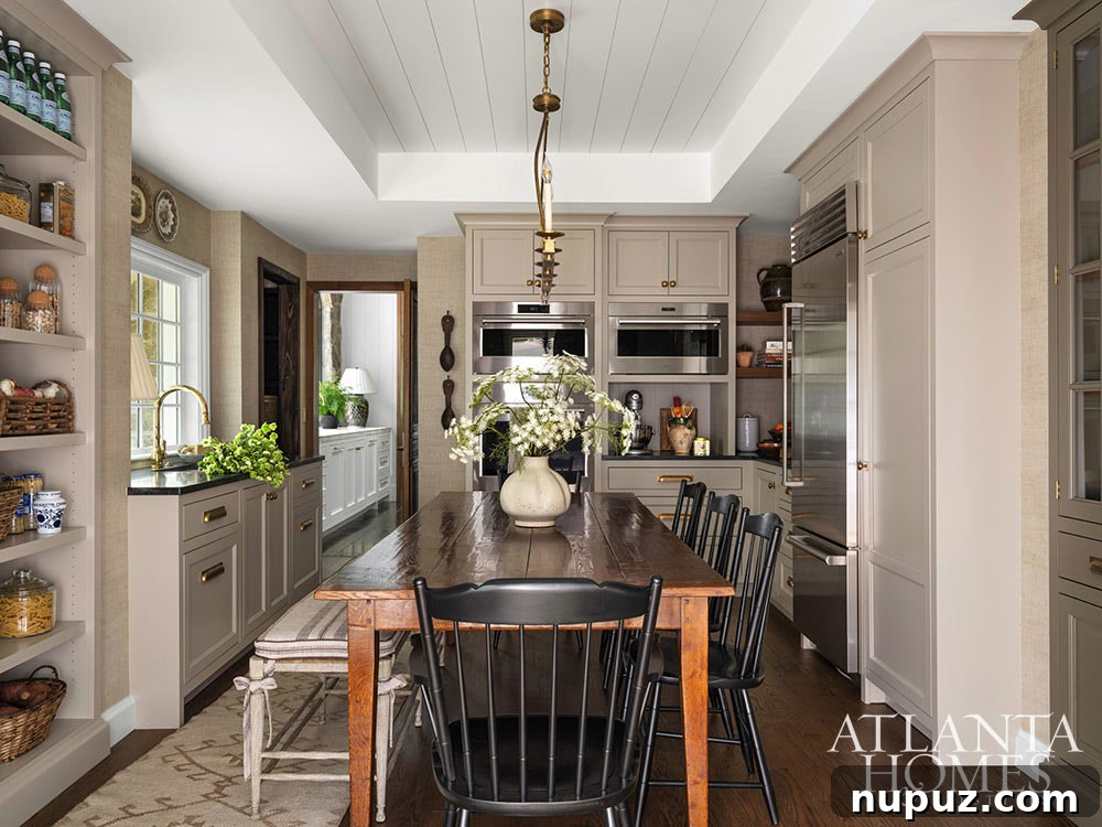 A spacious, bright kitchen featuring white custom cabinetry, a large island, professional-grade appliances, and chic pendant lighting.