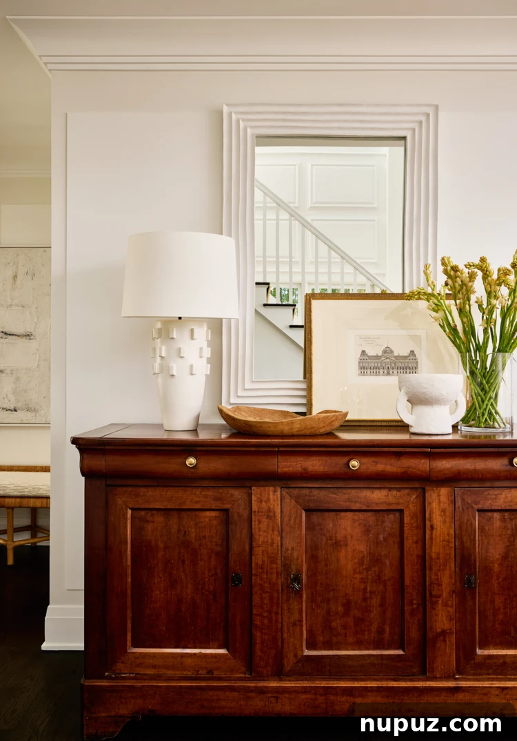 Foyer with elegant wood console and mirror, welcoming guests into a serene waterfront residence.
