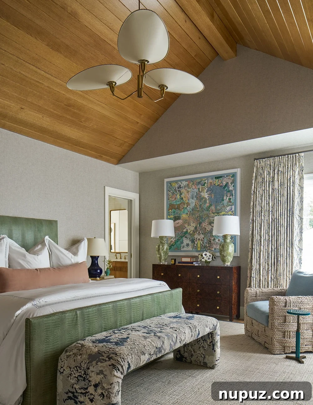 An elegant green upholstered bed serves as a stylish focal point, flanked by chic lighting fixtures, embodying classic bedroom design from Mary Beth Wagner Interiors and Nathan Schroder Photography.