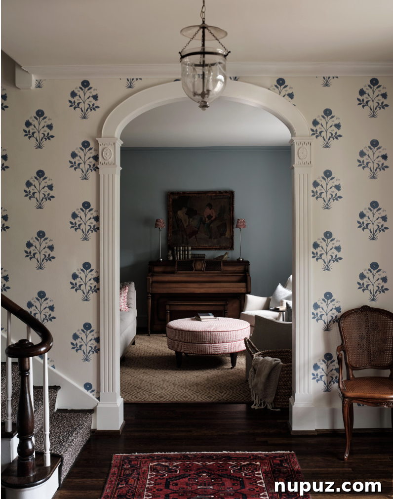 A grand wallpapered entry foyer with arched doorways and a striking bell jar lantern, designed by Sabbe Interior Design and photographed by Joseph Bradshaw. This space exemplifies a shift towards intentional room design.