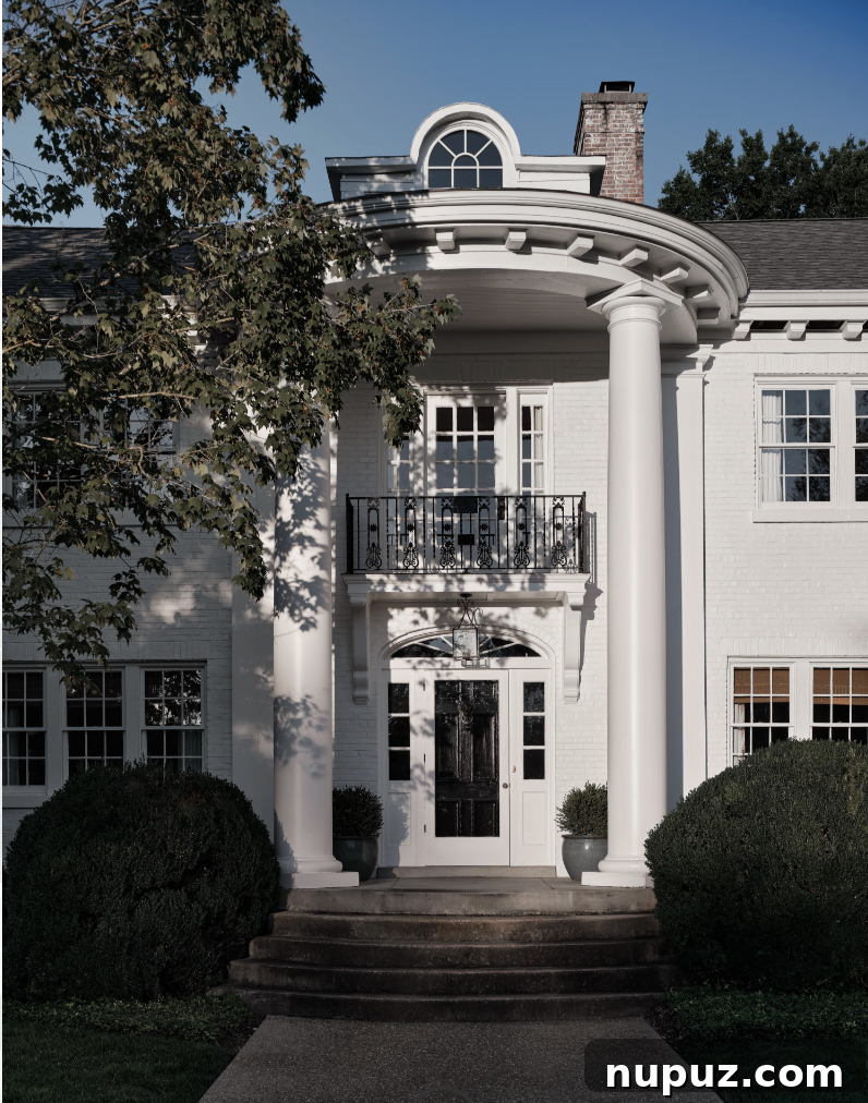 A beautiful white home exterior with elegant two-story columns, creating impressive curb appeal and hinting at the intentional design within, photographed by Joseph Bradshaw.
