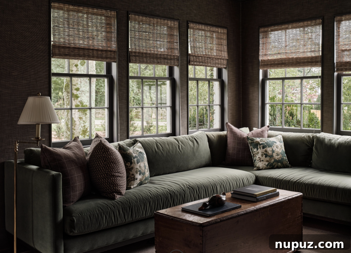 A cozy sitting room featuring a plush green velvet sectional sofa and natural texture of bamboo shades, designed by Sabbe Interior Design and captured by Joseph Bradshaw, reflecting the trend of rooms with a clear purpose.