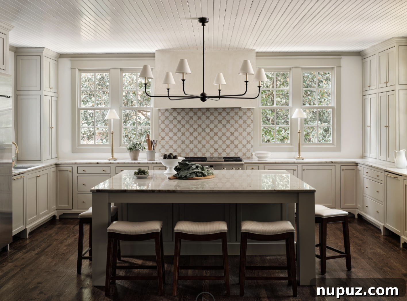 A beautifully designed white kitchen by Sabbe Interior Design, featuring a paneled ceiling and a central island, photographed by Joseph Bradshaw. This space combines elegance with functional purpose.
