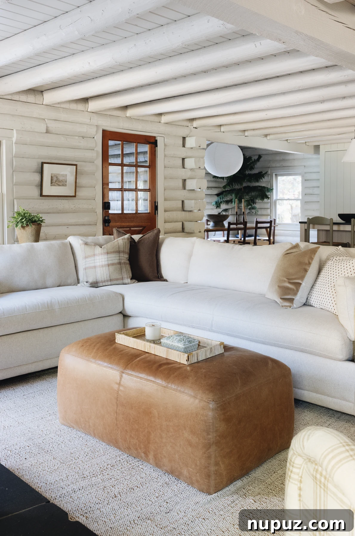 A calm living room is never dull. Adding texture from woven baskets, natural fiber rugs, nubby upholstery, and beautiful antiques combine to create a room that feels livable rather than sterile. Jean Stoffer Interior Design | Stoffer Photography Interior - love the log cabin painted white inside with white sectional sofa and leather ottoman