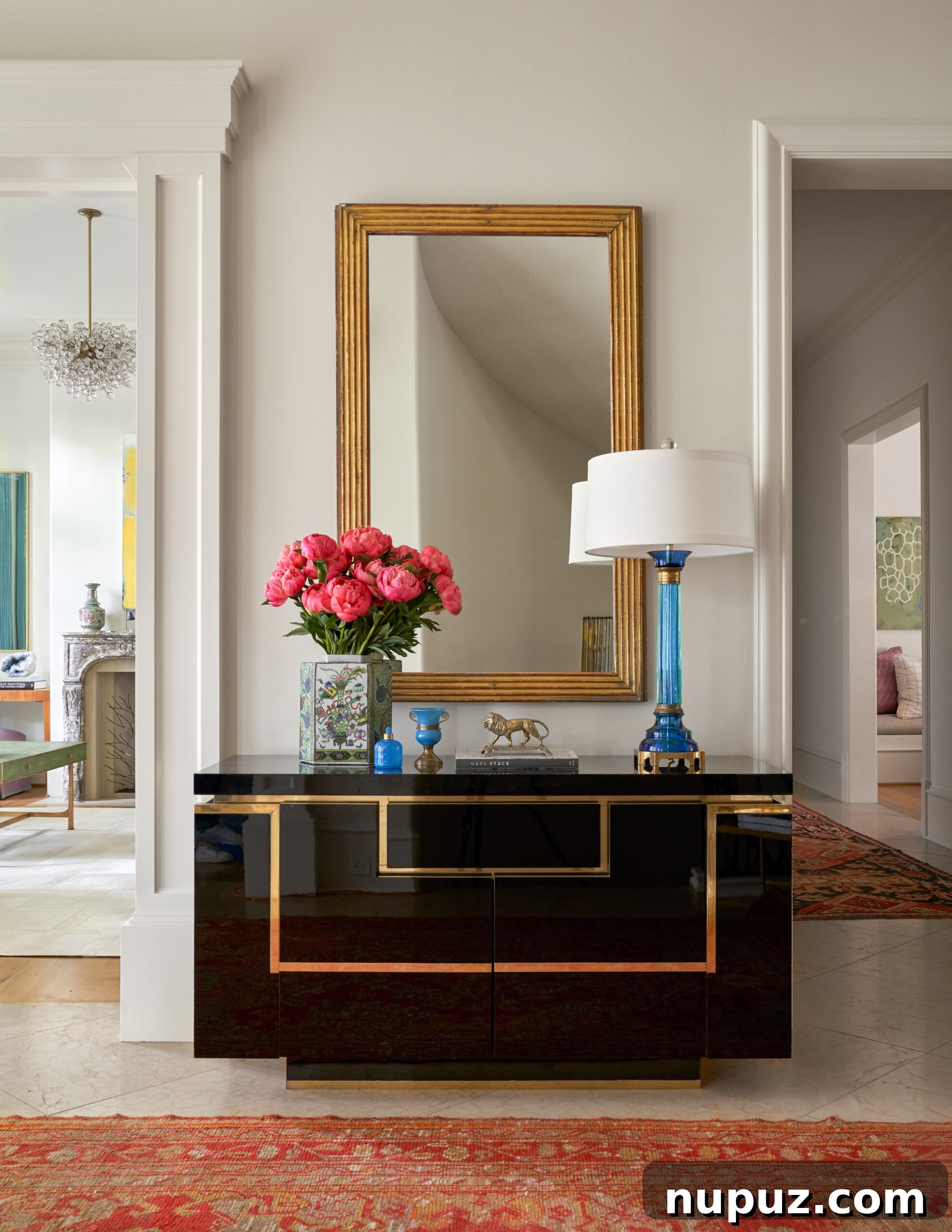 7 Entryway Transformations for an Impressive Welcome 2 Grand foyer with a round center table adorned with a lush floral arrangement, classic architectural details, and a sophisticated chandelier by Collins Interiors.