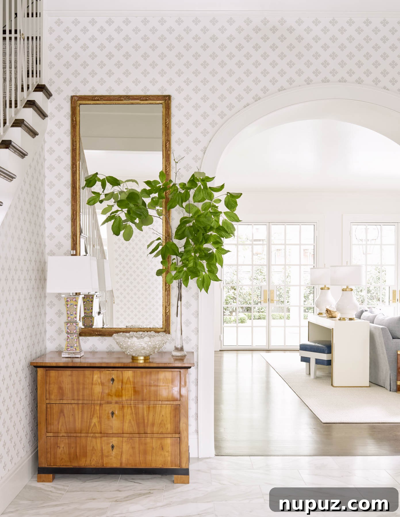 7 Entryway Transformations for an Impressive Welcome 4 Cozy and inviting foyer with a classic console, decorative mirror, and subtle lighting, creating a warm and personalized ambiance by Collins Interiors.
