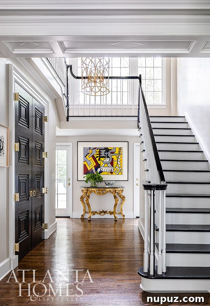 Stunning Atlanta Home Interiors 2 Grand entry foyer with striking black doors, a modern handrail, dark risers, and a vibrant, colorful modern art piece, setting a sophisticated tone.