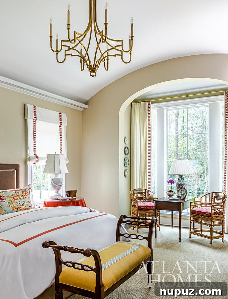 Stunning Atlanta Home Interiors 13 A cozy bedroom setting featuring a stylish bench at the end of the bed and two elegant chairs nestled in a sunlit bow window, inviting relaxation.