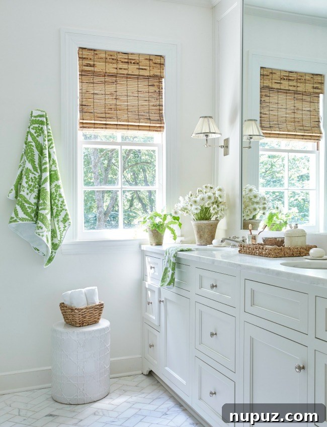 A pristine white bathroom with strategic touches of green, illustrating Sarah Bartholomew's ability to balance color and simplicity.
