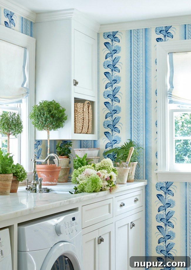 A beautifully organized blue and white laundry room designed by Sarah Bartholomew, featuring shelving, a sink, and elegant decor.