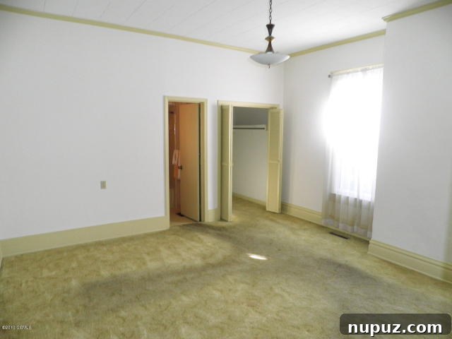 Downstairs master bedroom in disarray, showing worn carpet and walls