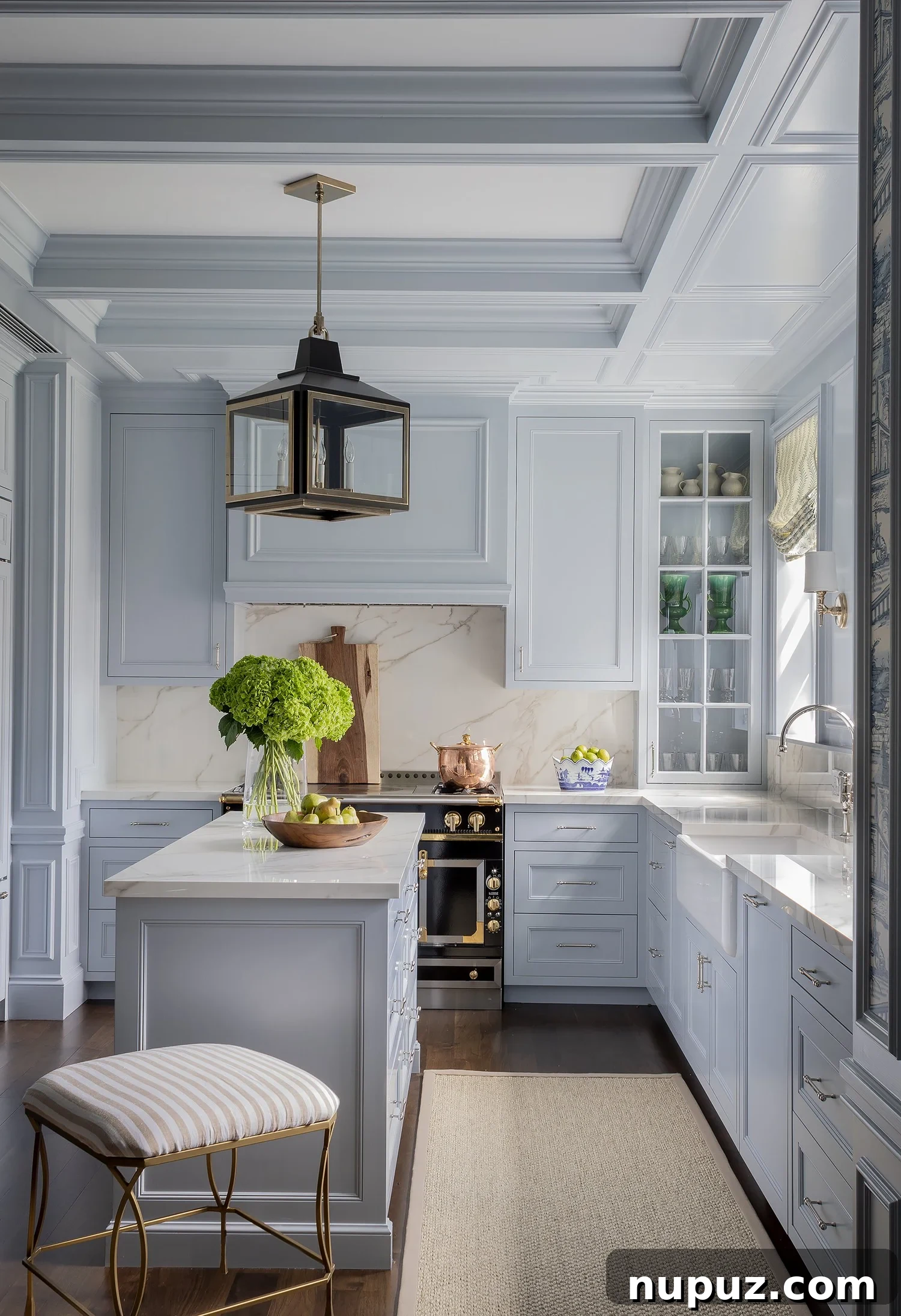 Stunning blue kitchen with painted ceiling beams and black lanterns over the island, demonstrating layered lighting.