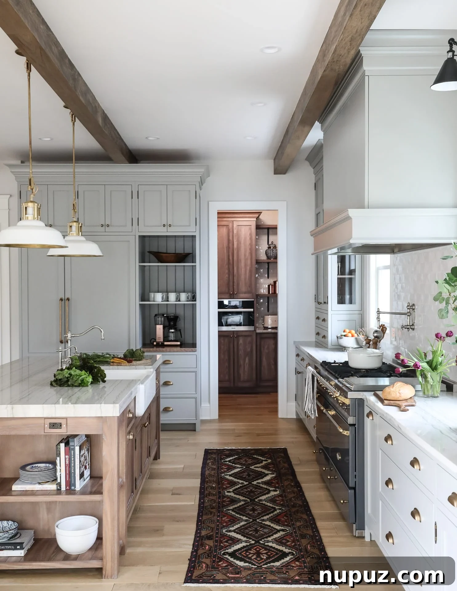 Elegant kitchen with dark blue shaker cabinets, brass fixtures, and a white marble countertop by Park and Oak Design, highlighting a trend towards darker, richer tones.