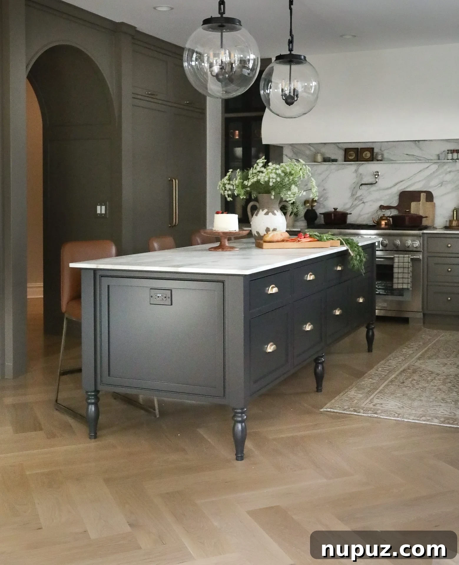 Spacious kitchen featuring deep forest green cabinetry, a large central island with seating, and warm wooden flooring, designed by Park and Oak.