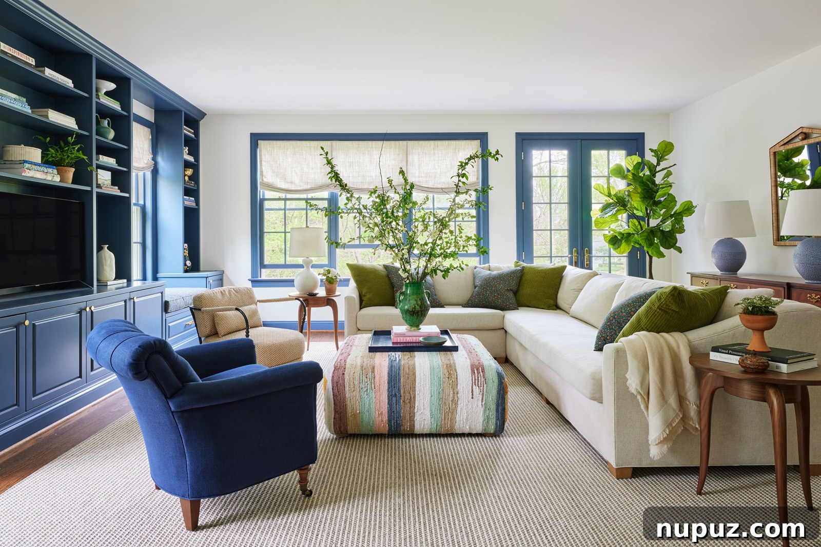 Elegant blue living room by Jennifer Hunter featuring a comfortable white sectional sofa and a vibrant, colorful coffee table, photographed by Kristen Francis.