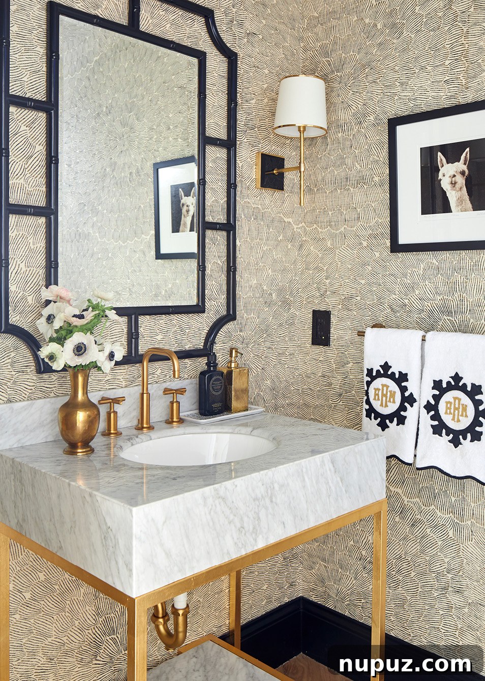 Luxurious powder room featuring a navy blue Serena and Lily mirror, a bold Schumacher wallpaper, and elegant fixtures for a sophisticated small space design by Amanda Reynal.