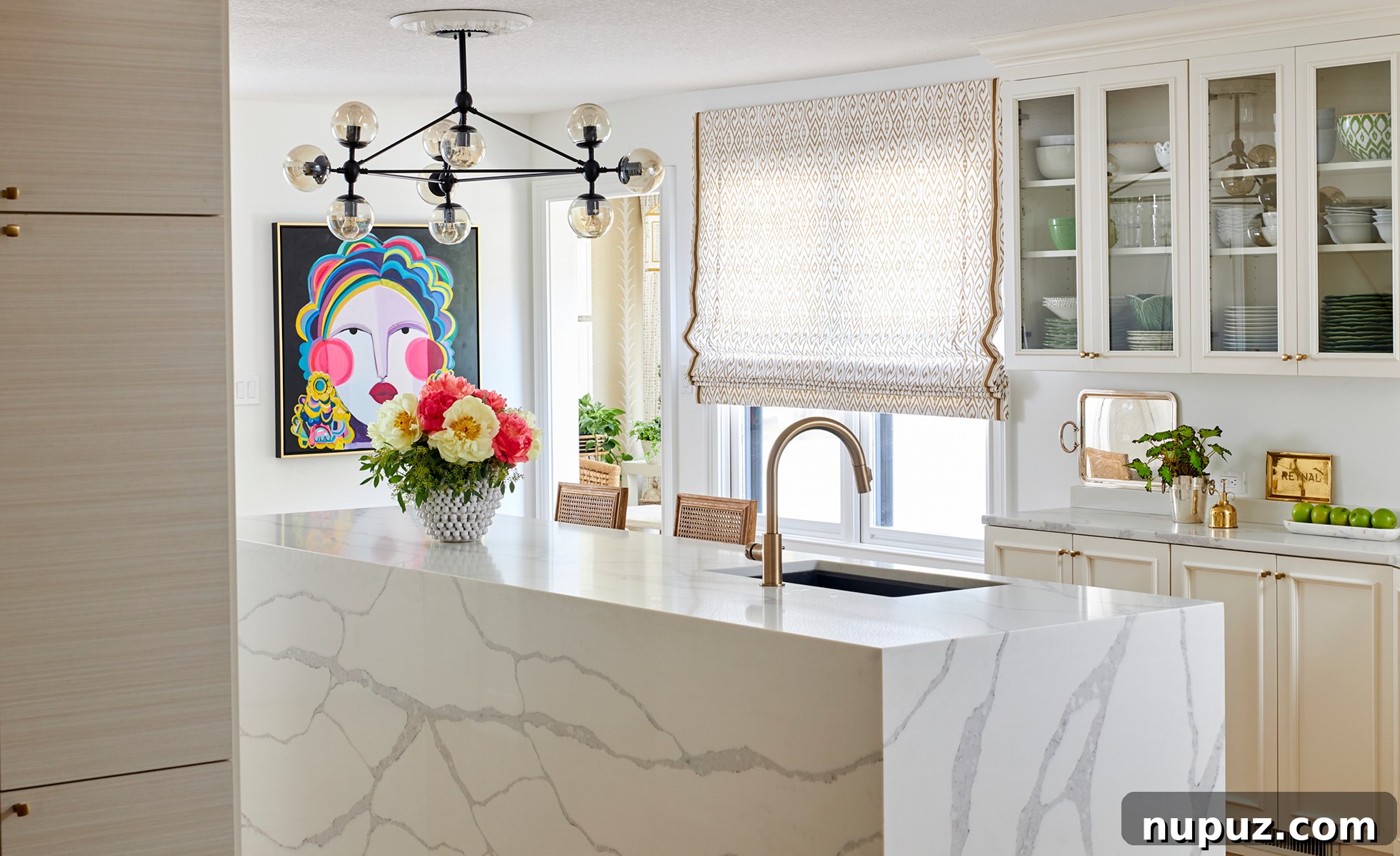 Modern kitchen with a vibrant face art piece, pristine white cabinetry, and a clean, minimalist aesthetic, designed by Amanda Reynal.