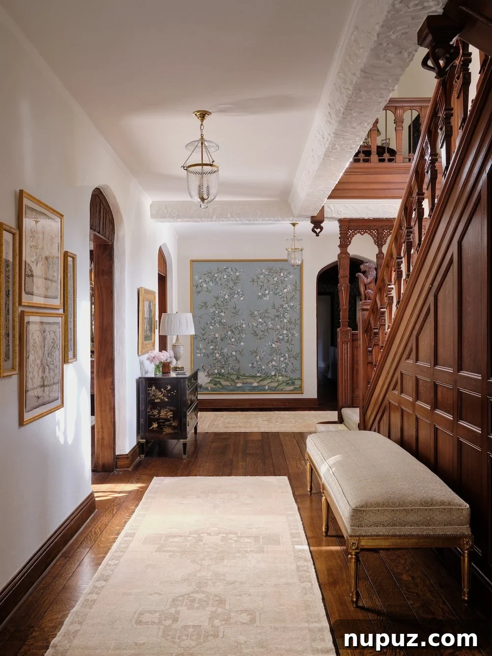 Foyer with arched doorways, bell jar lantern, and stained staircase showcasing Jenkins Interiors' blend of old and new design.