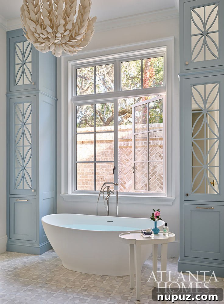 An elegant blue and white bathroom in the Sea Island home, featuring a luxurious freestanding tub and a chic Palacek light fixture, creating a serene, spa-like retreat.