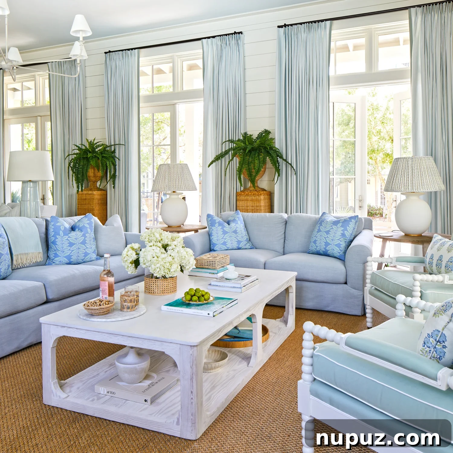 Breezy Blue and White Coastal Bliss 2 Stunning blue and white beach house living room with transom windows, wicker planters, and a curated coastal aesthetic by Kara Miller Interiors.