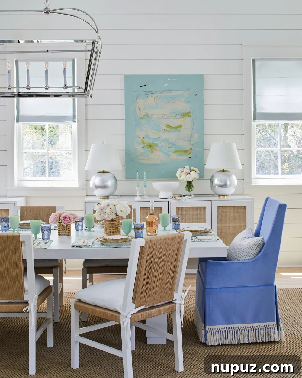 Breezy Blue and White Coastal Bliss 5 Coastal dining room featuring captivating abstract art on a shiplap wall, harmonizing with the blue and white palette in this Kara Miller-designed beach house.