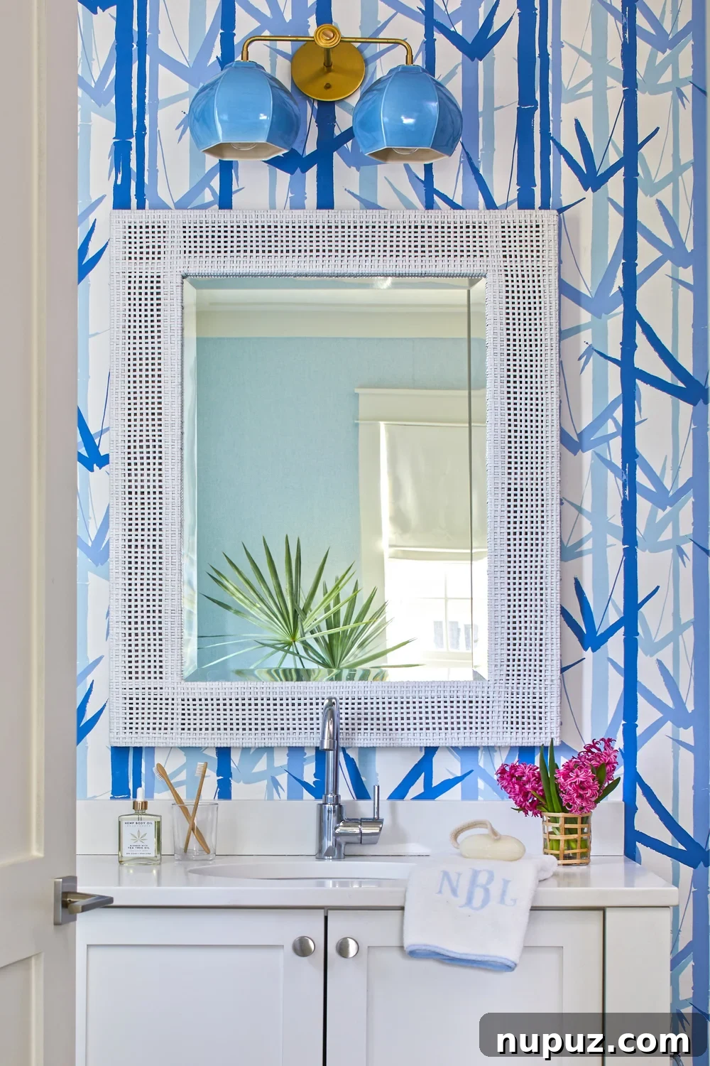 Breezy Blue and White Coastal Bliss 8 Charming blue and white beach house bathroom featuring delightful palm leaf wallpaper, exemplifying Kara Miller's fresh and inviting coastal design.