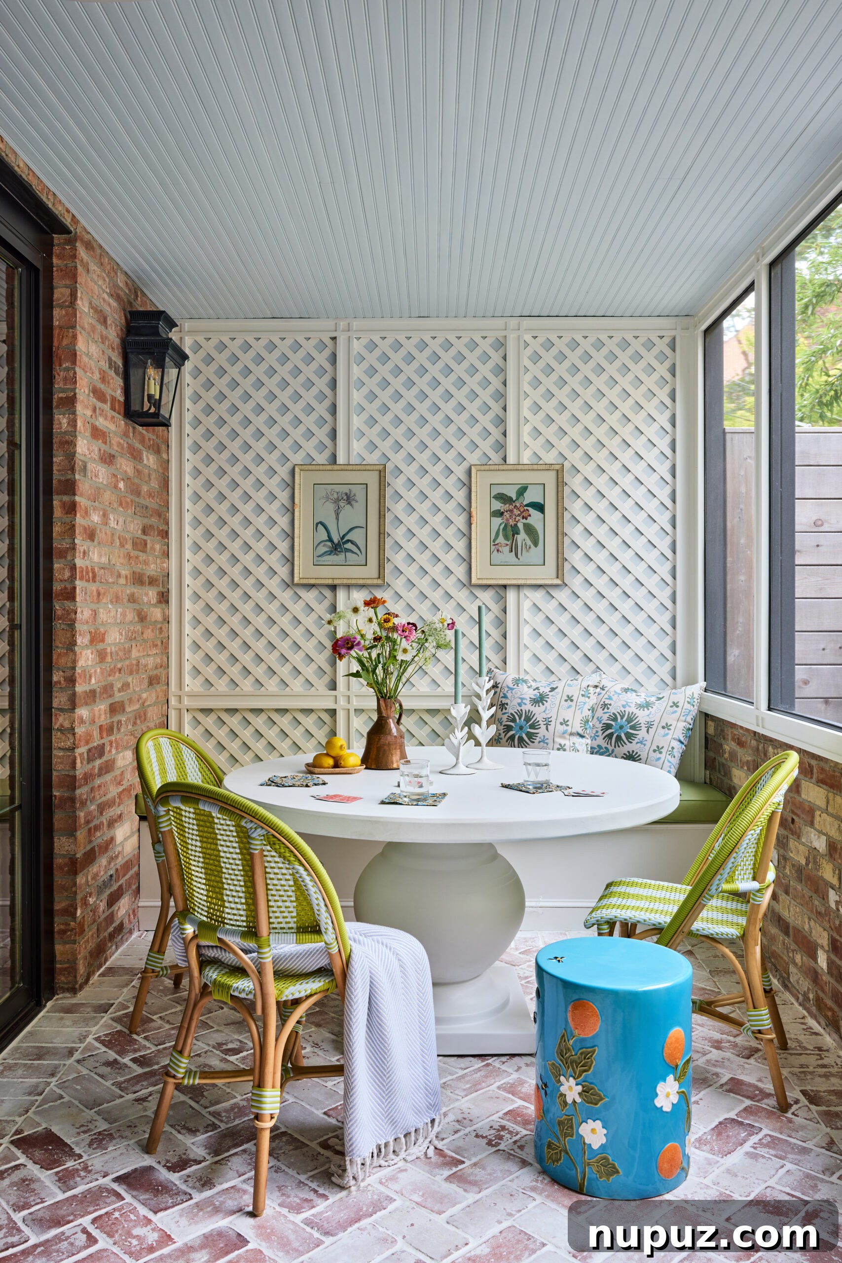 Charming covered porch with a round dining table and green Riviera chairs