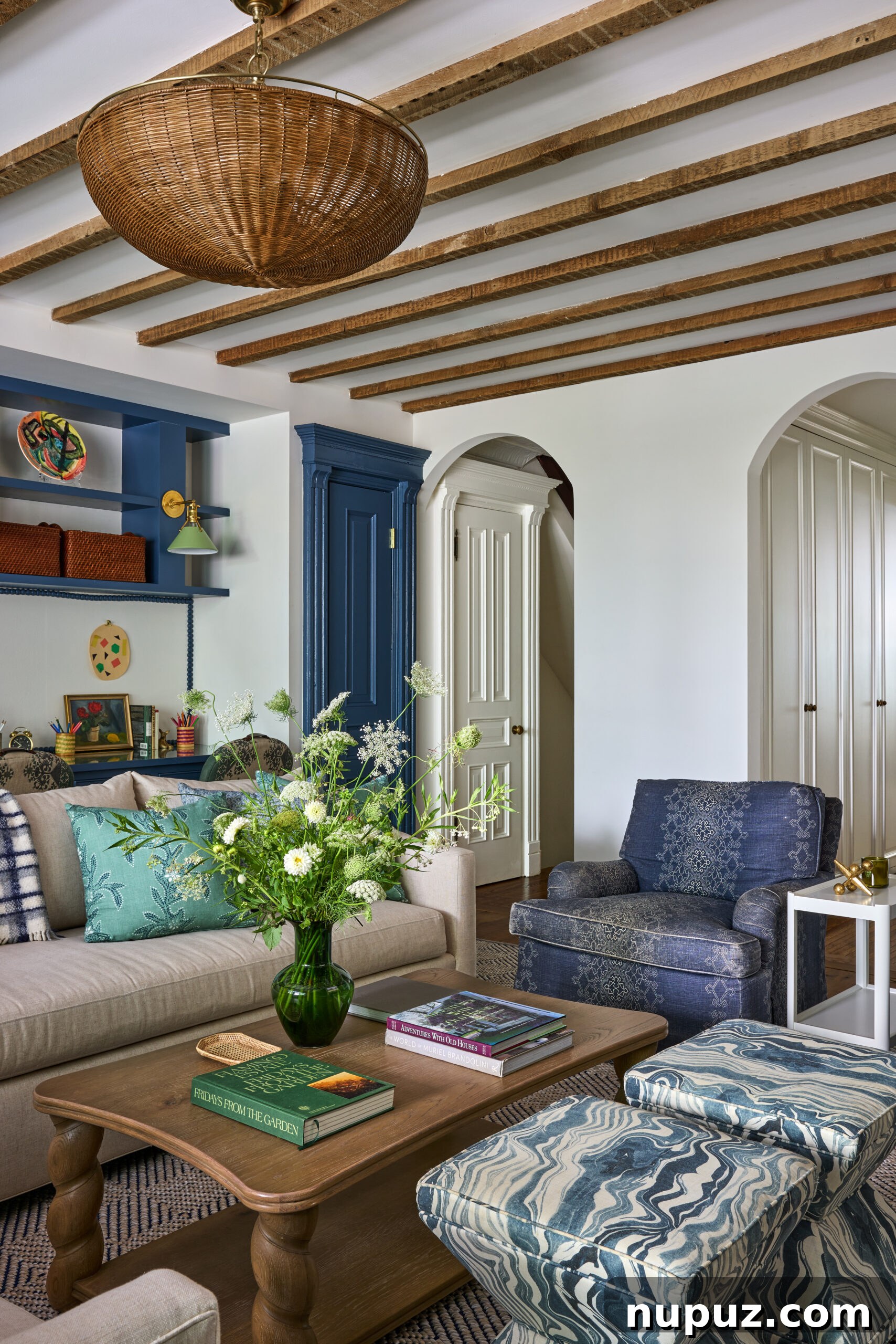 Living room with exposed wood beams, arched doorways, and a Visual Comfort wicker chandelier