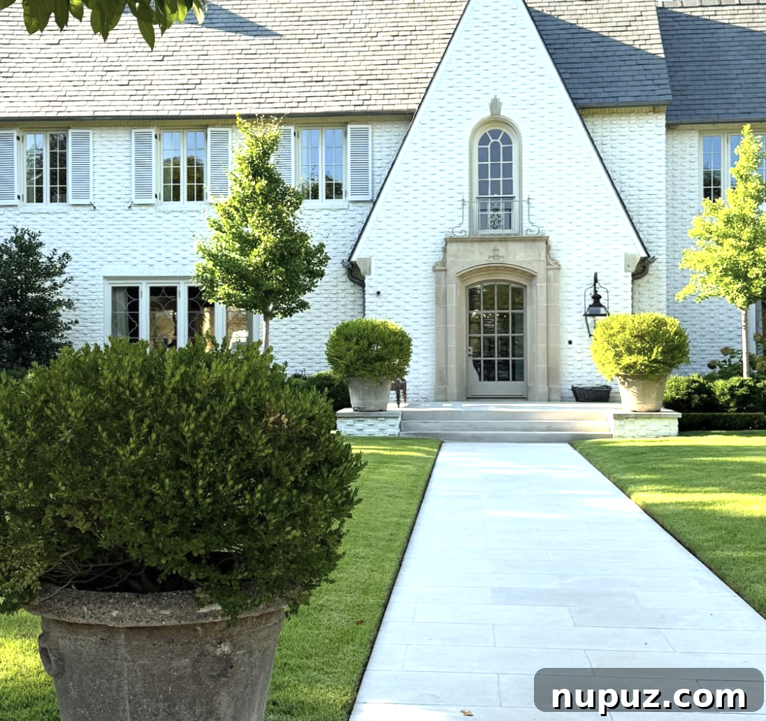 7 Homes Where Boxwoods Command the Landscape 5 Elegant home entrance framed by topiaries and low boxwood hedges, enhancing the architectural symmetry and welcoming appeal.