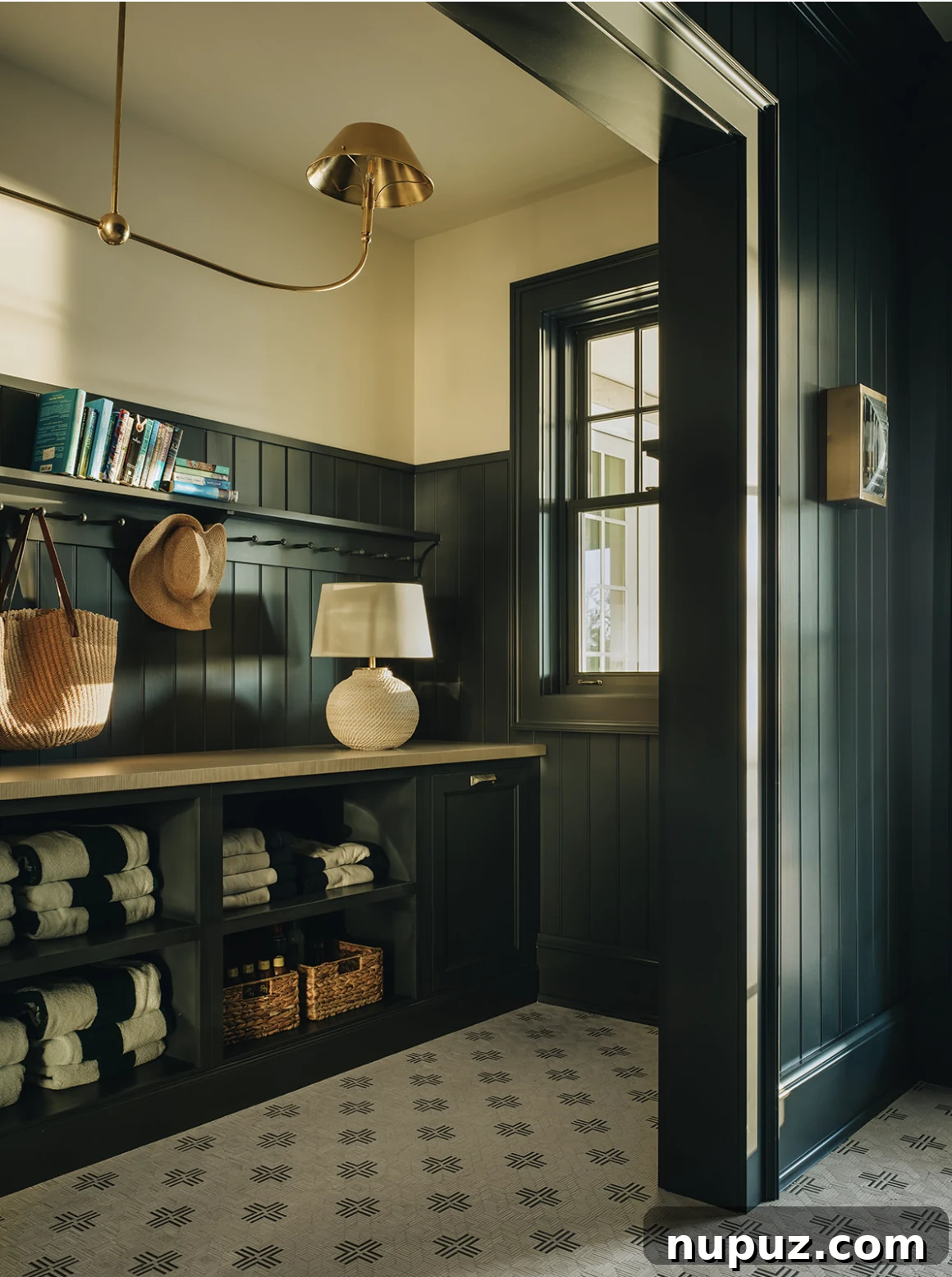 Sophisticated mudroom by Jean Stoffer Design with dark paint, a patterned rug, and a brass Visual Comfort chandelier