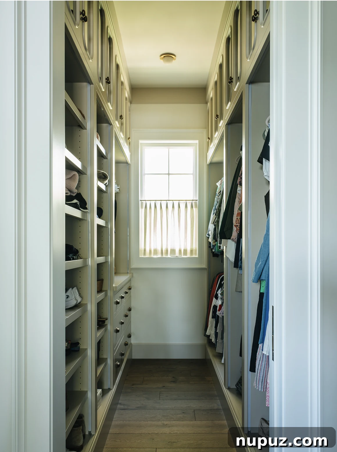 Luxury walk-in closet with extensive built-in storage by Jean Stoffer Design in a lake house