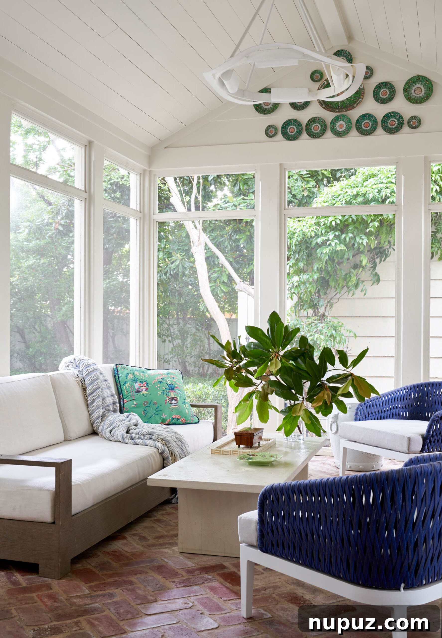 coffee table decor - screened porch with beautiful light fixture and blue wicker chairs - Collins Interiors | Nathan Schroder Photography